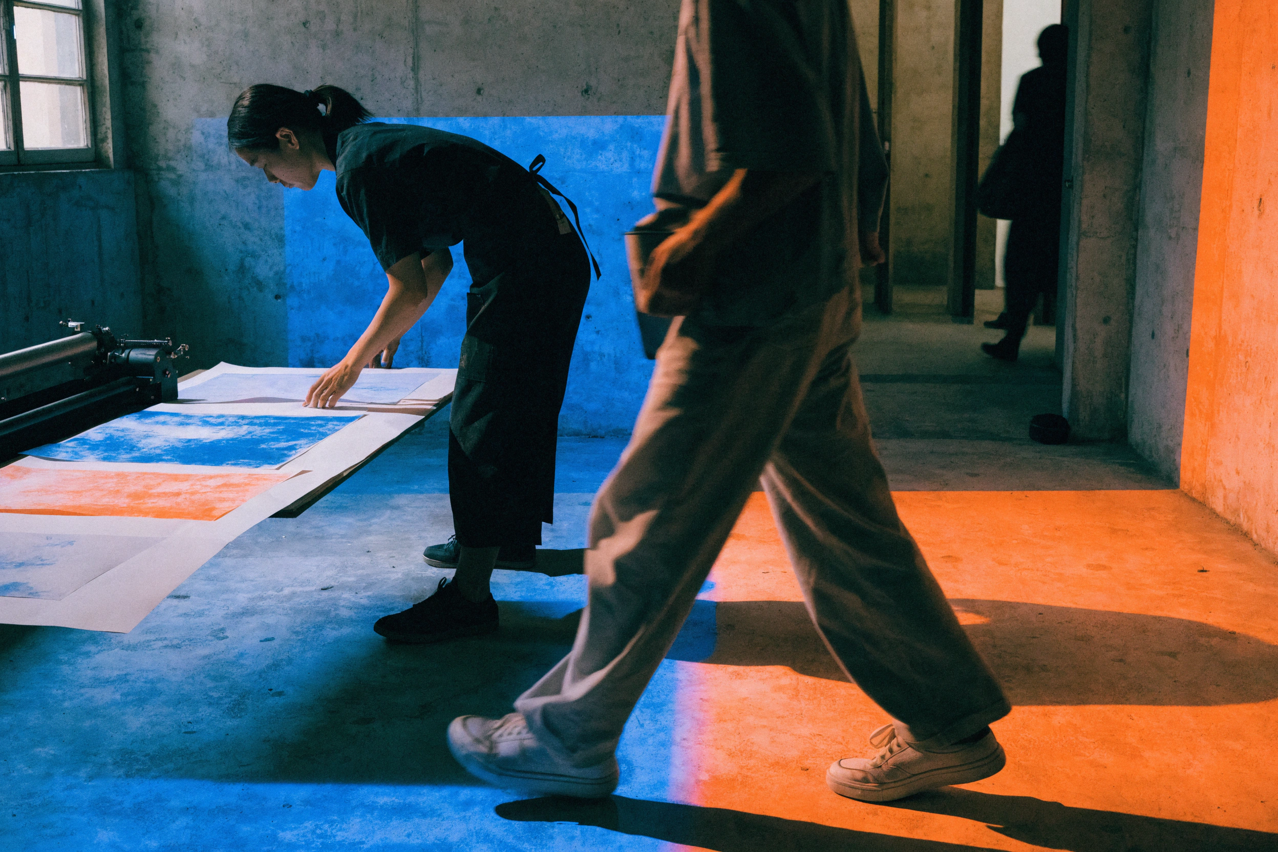 Viewers crossing overlapping cobalt and orange projections while the programme text stays fixed.