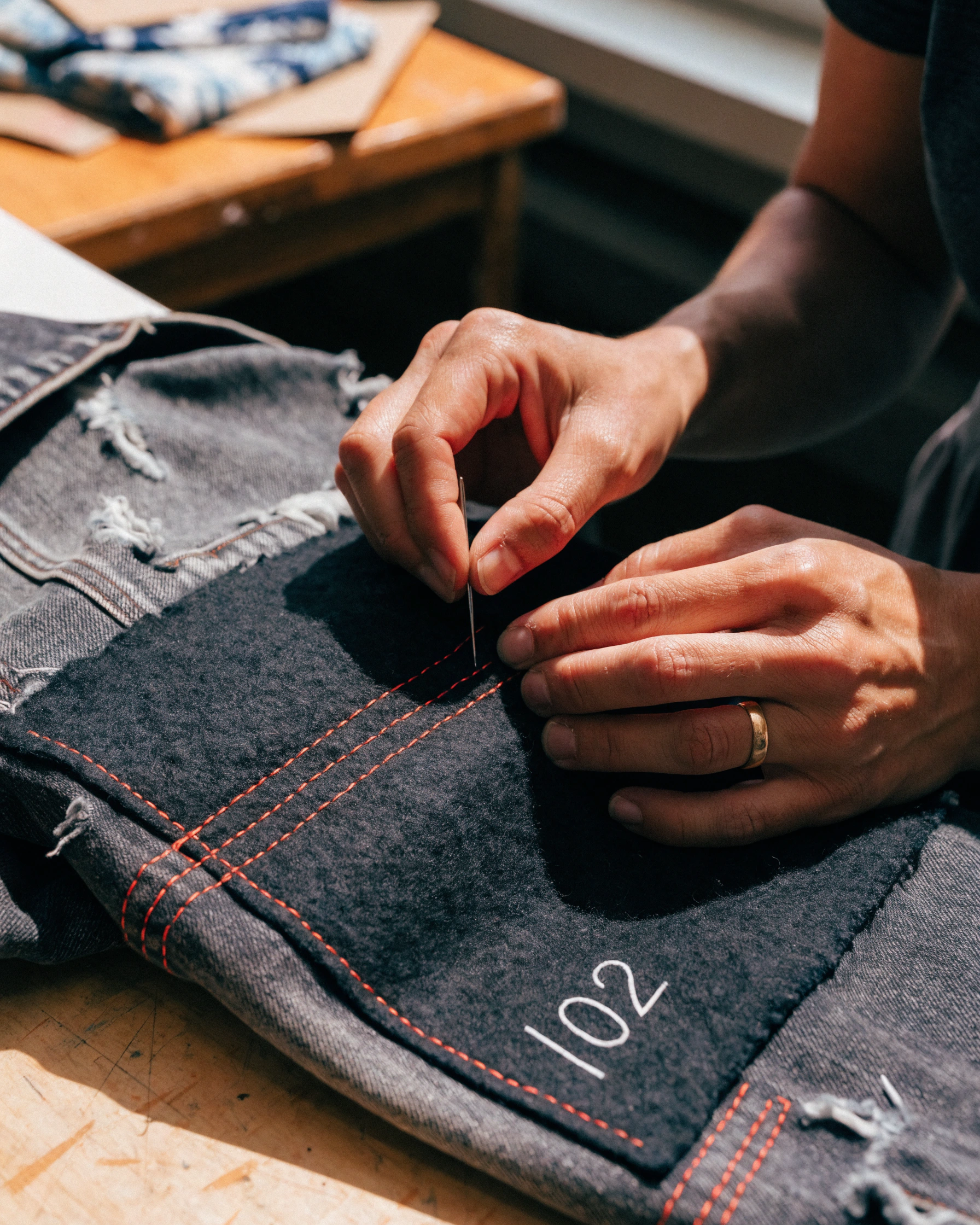 A maker stitches the damaged panel with contrast thread and adds the next code.