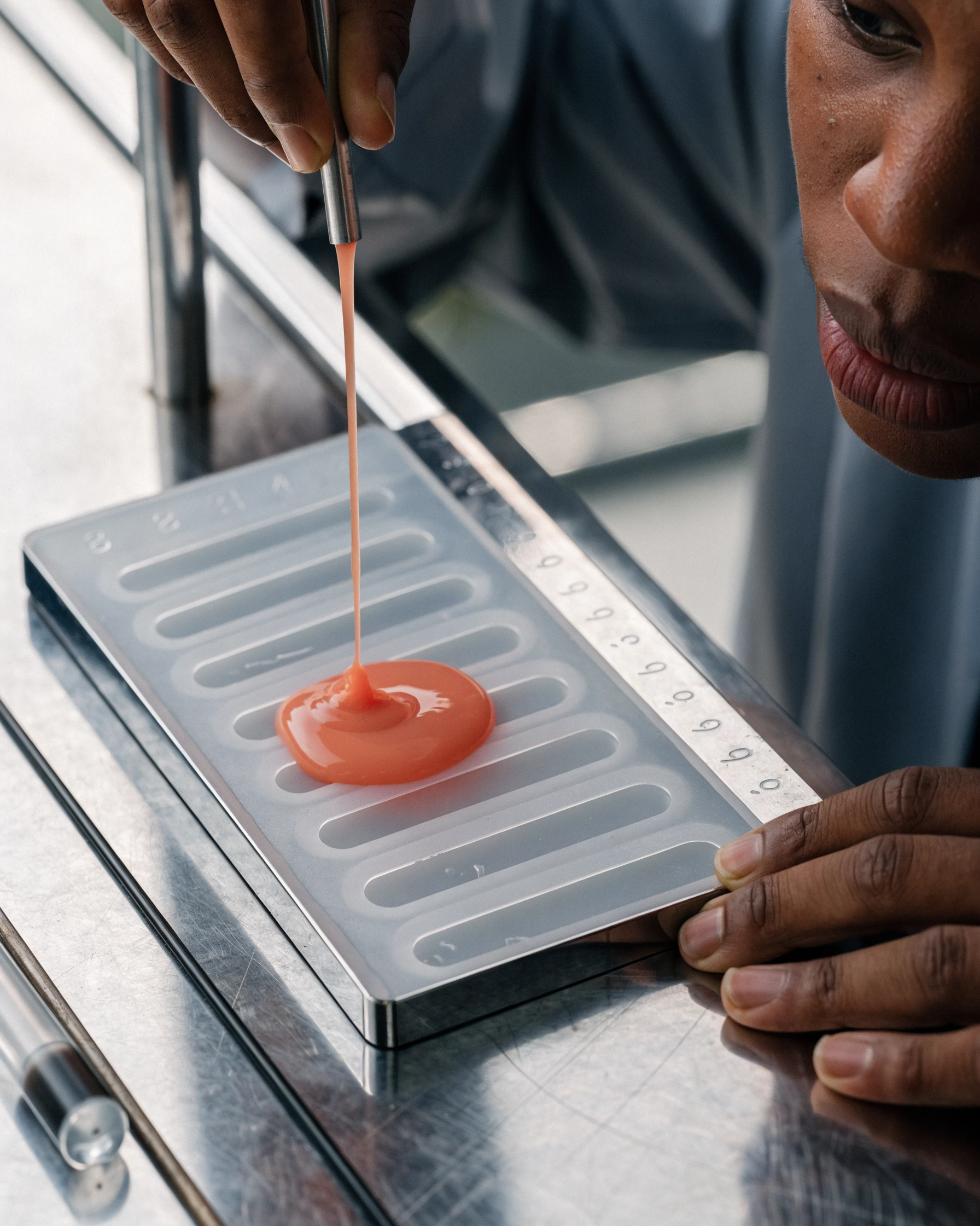 A technician pours pigmented silicone into a numbered translucent mould.